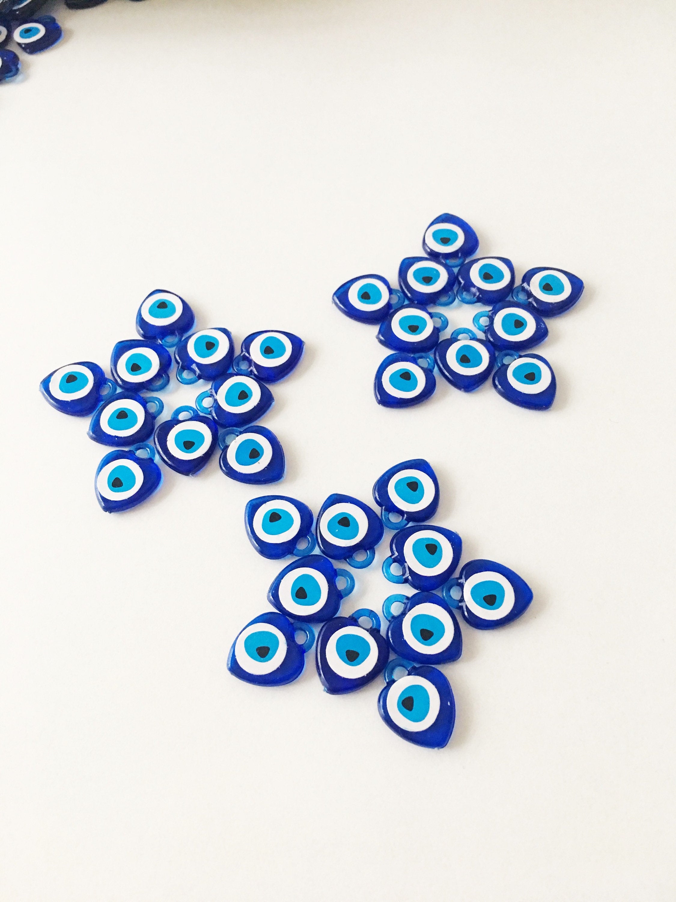 A collection of 100 blue evil eye charms made from resin, showcasing their vibrant color and intricate design, perfect for wedding and party favors.