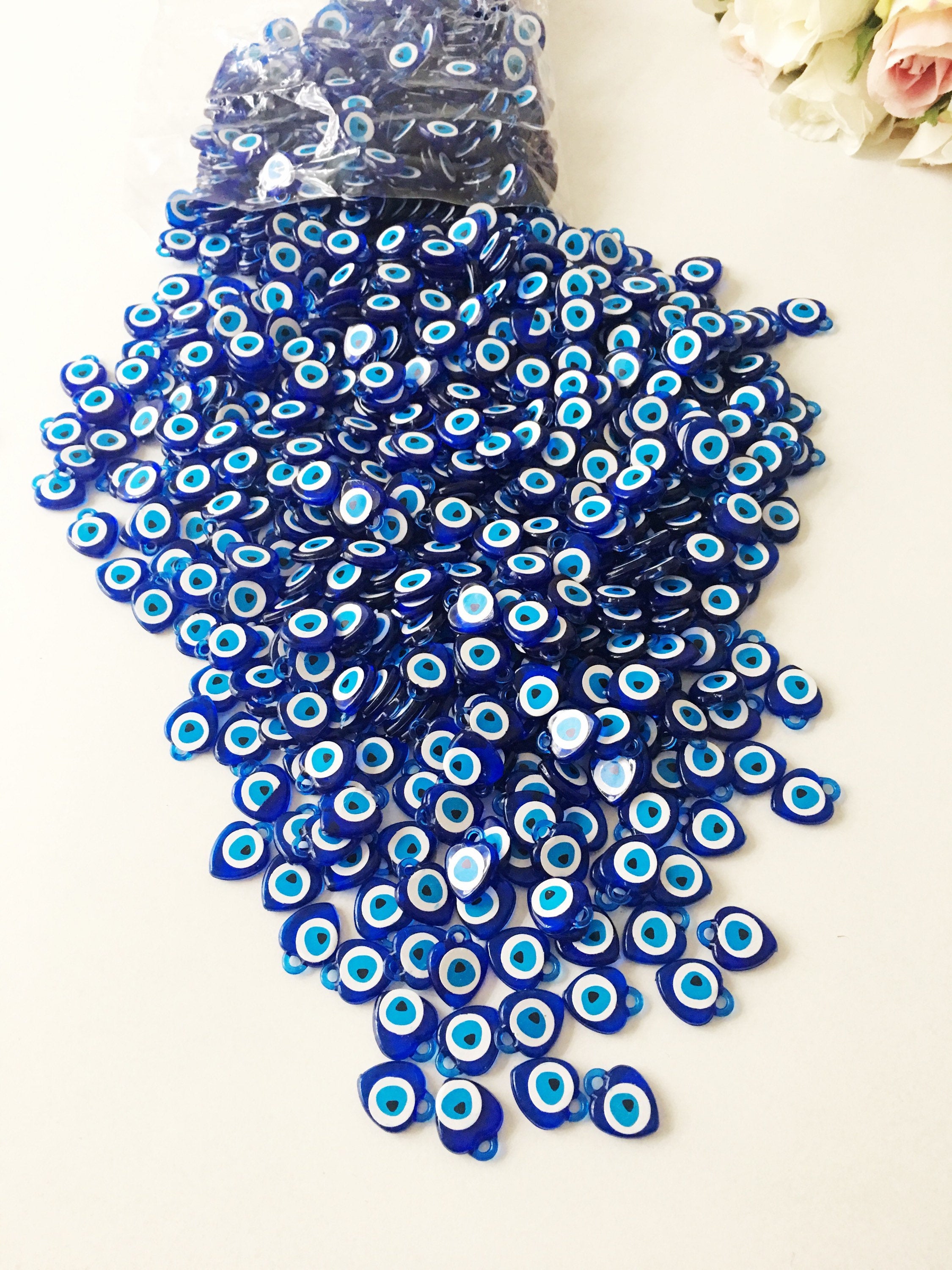 A collection of 100 blue evil eye charms made from resin, showcasing their vibrant color and intricate design, perfect for wedding and party favors.