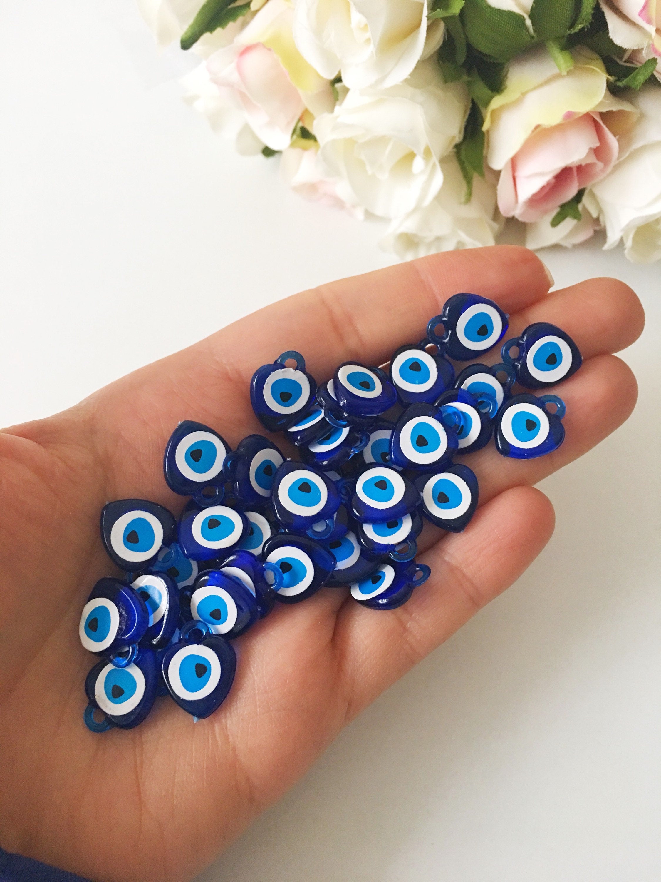 A collection of 100 blue evil eye charms made from resin, showcasing their vibrant color and intricate design, perfect for wedding and party favors.