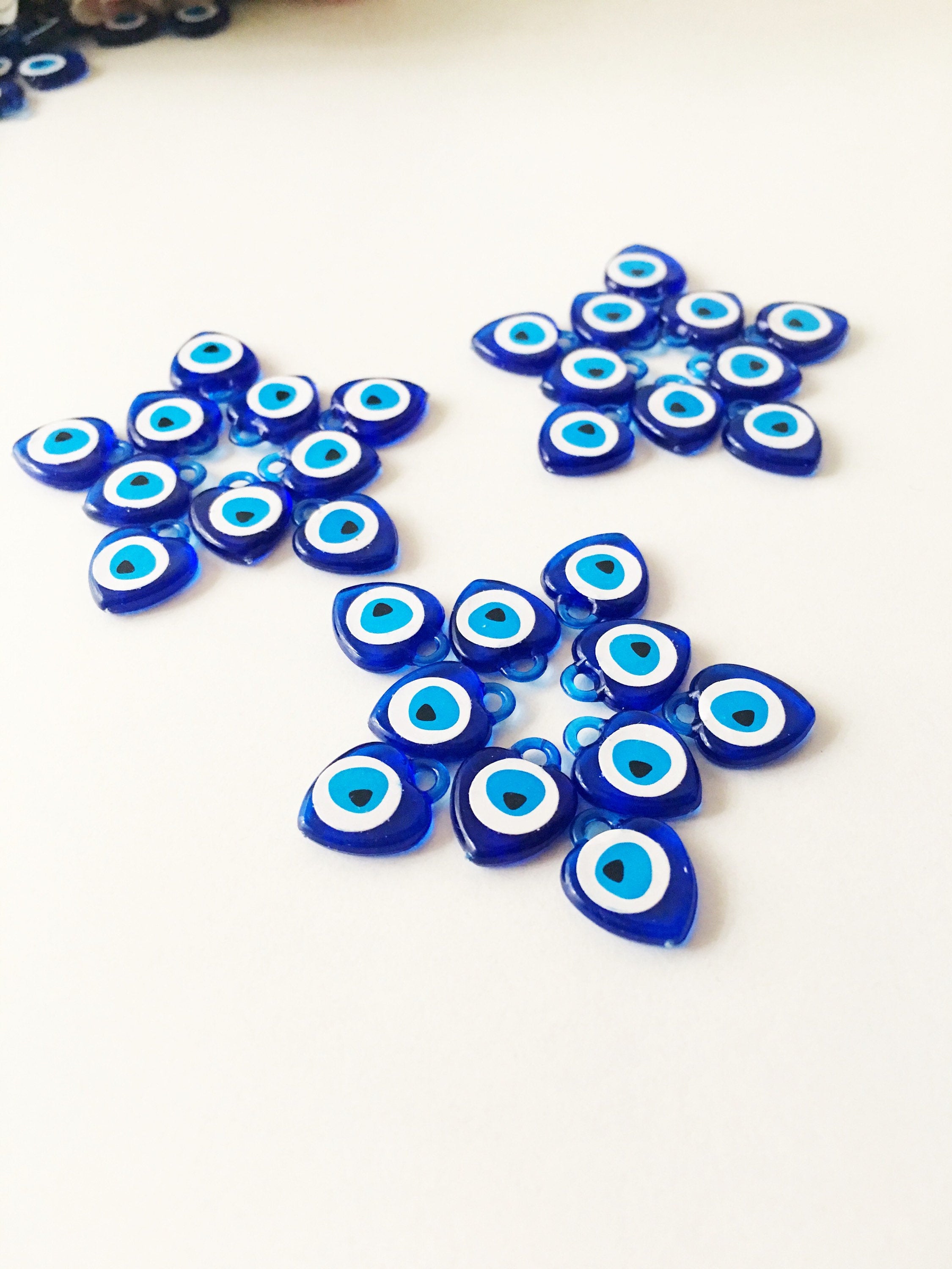 A collection of 100 blue evil eye charms made from resin, showcasing their vibrant color and intricate design, perfect for wedding and party favors.