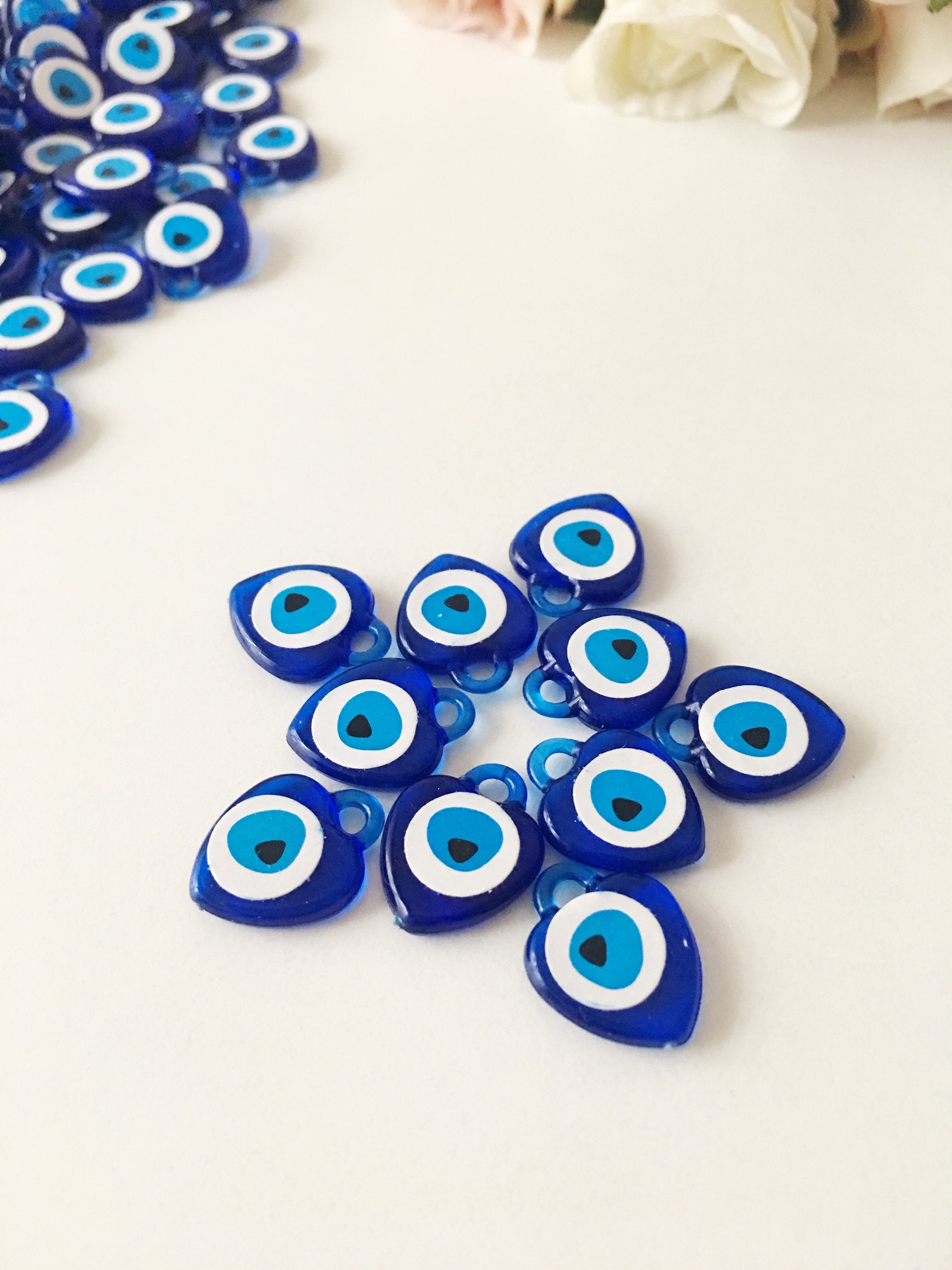 A collection of 100 blue evil eye charms made from resin, showcasing their vibrant color and intricate design, perfect for wedding and party favors.