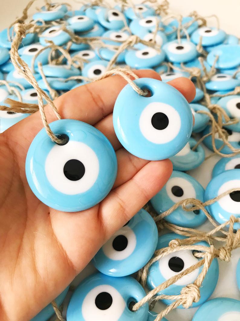 A collection of 100 blue glass evil eye beads, each 4.5 cm, with blue ropes for hanging, perfect as wedding favors.