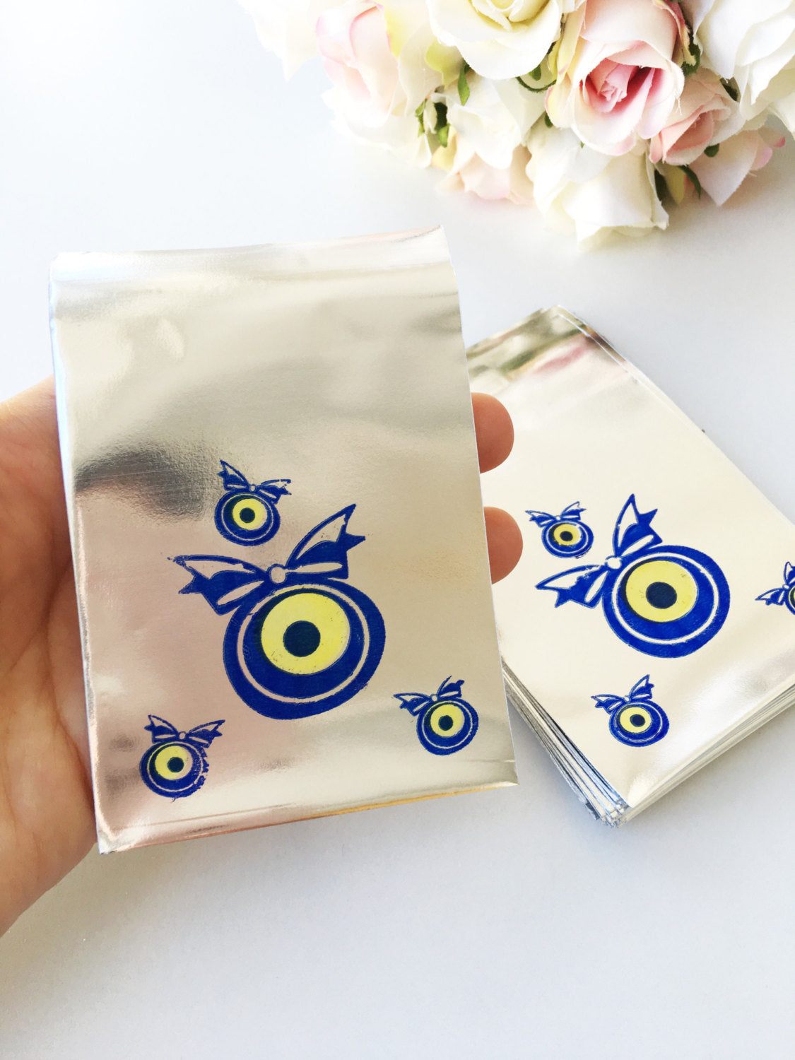 A collection of 100 pcs evil eye bags featuring vibrant blue and white designs, perfect for gifts and coins.