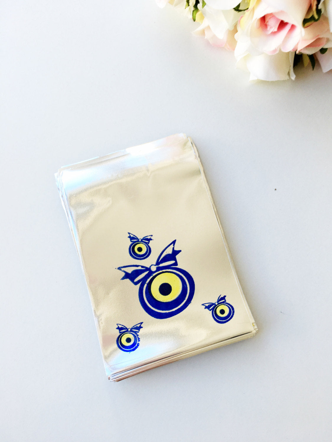 A collection of 100 pcs evil eye bags featuring vibrant blue and white designs, perfect for gifts and coins.