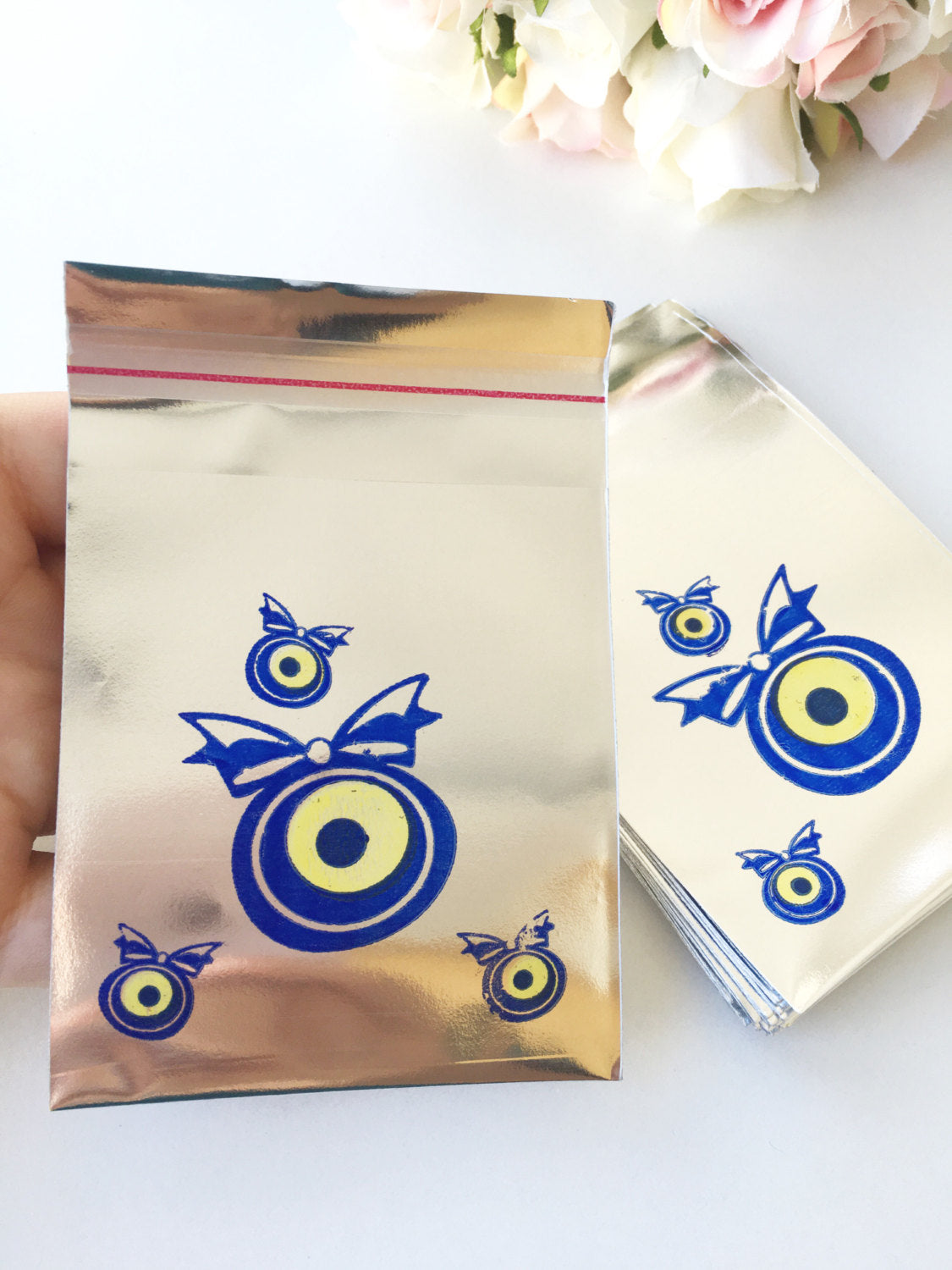 A collection of 100 pcs evil eye bags featuring vibrant blue and white designs, perfect for gifts and coins.