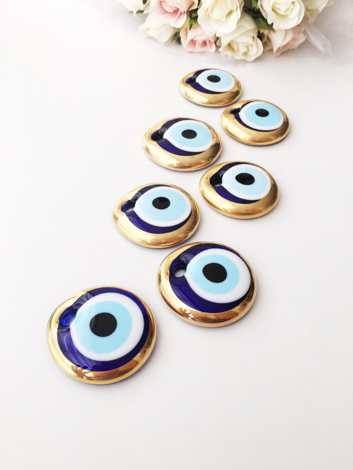 A set of 10 handmade evil eye charms featuring gold glass beads, ready for wall hanging or car decor, showcasing unique designs.