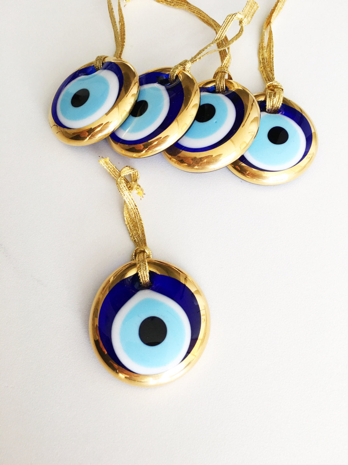 A set of 10 handmade evil eye charms featuring gold glass beads, ready for wall hanging or car decor, showcasing unique designs.