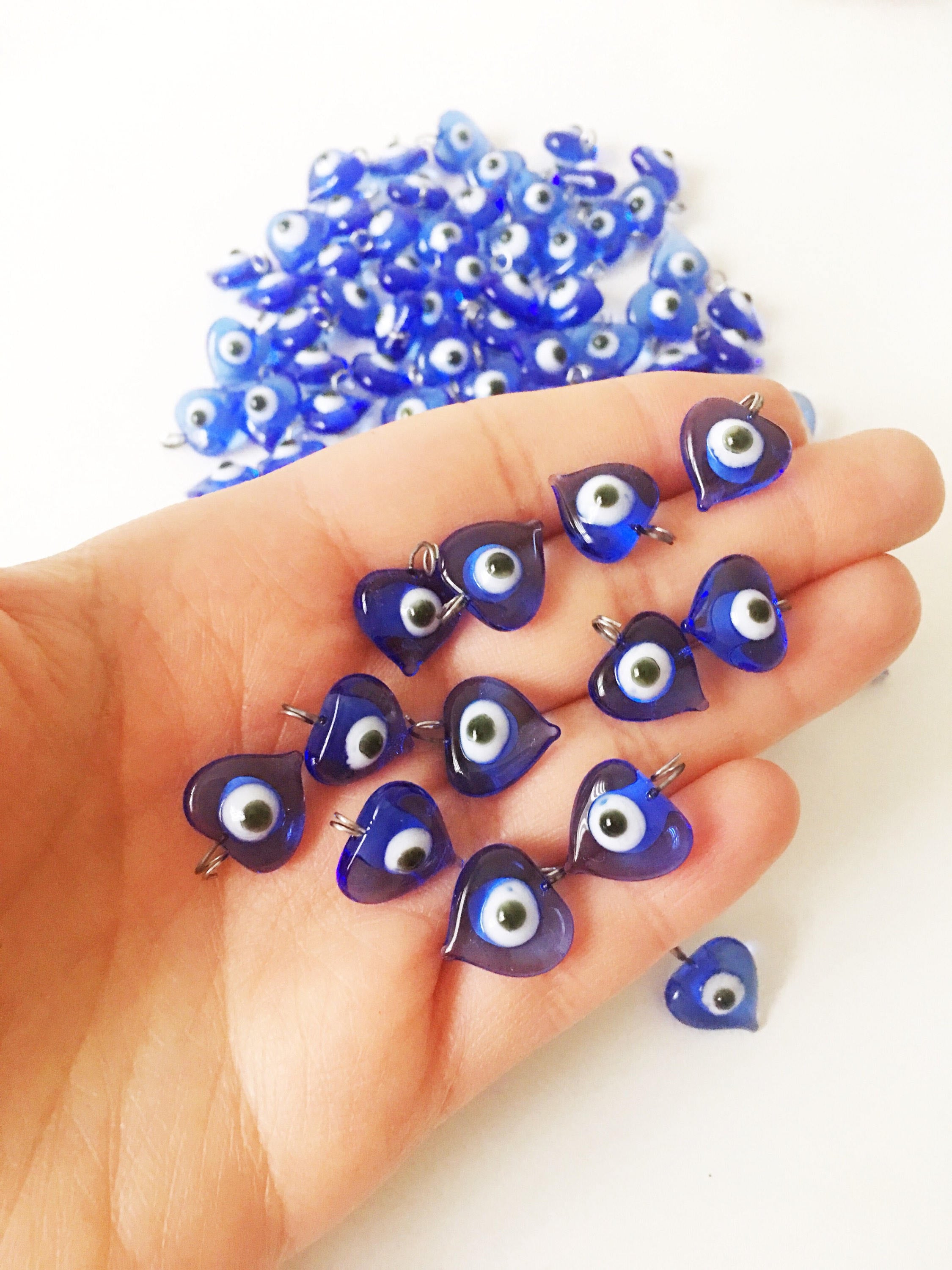 A collection of 100 unique blue evil eye charms with hooks, perfect for wedding favors and baby showers, displayed elegantly.