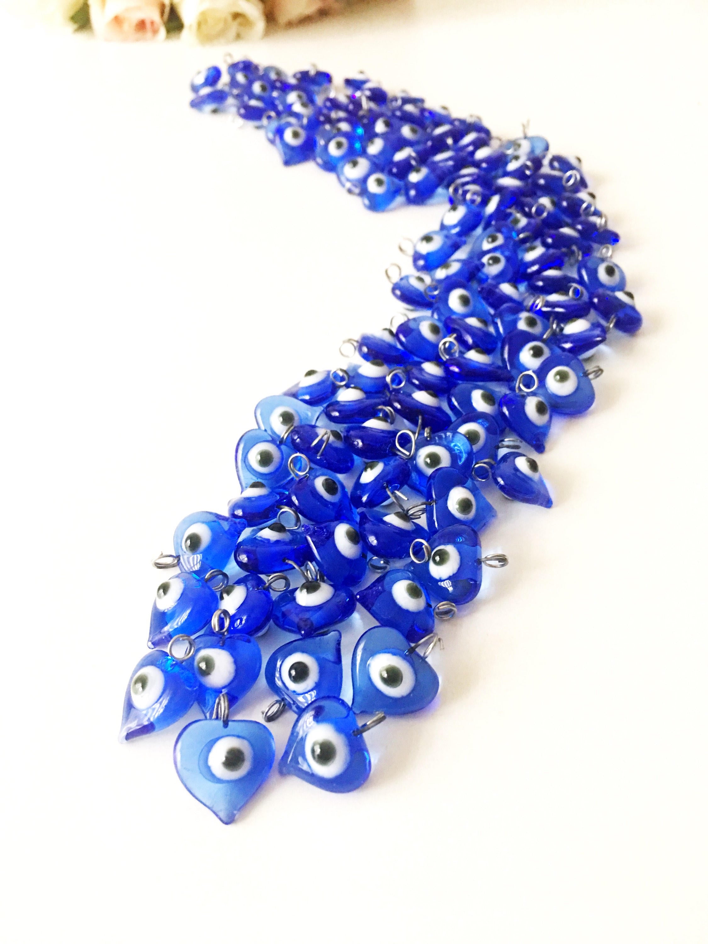 A collection of 100 unique blue evil eye charms with hooks, perfect for wedding favors and baby showers, displayed elegantly.