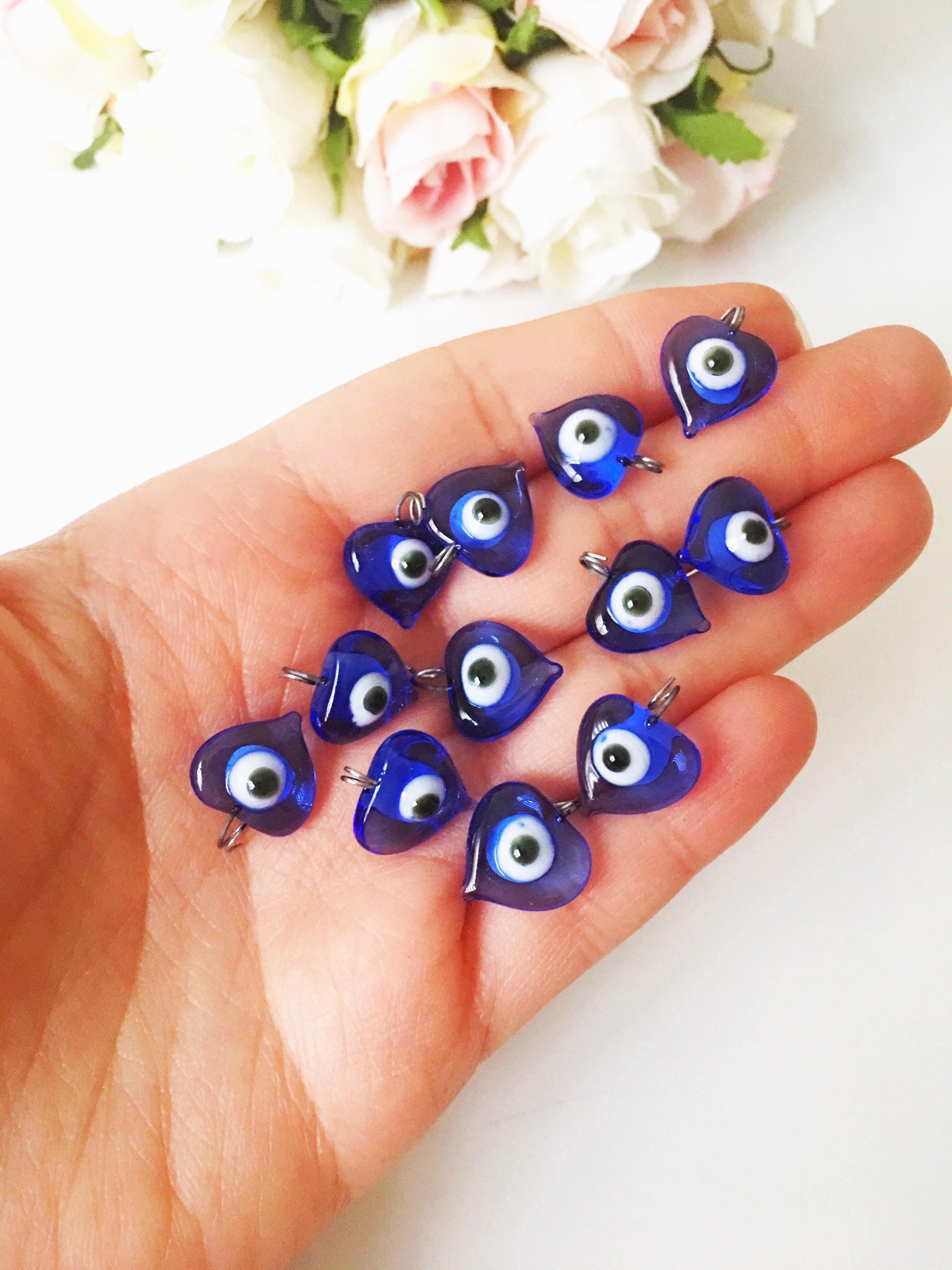 A collection of 100 unique blue evil eye charms with hooks, perfect for wedding favors and baby showers, displayed elegantly.