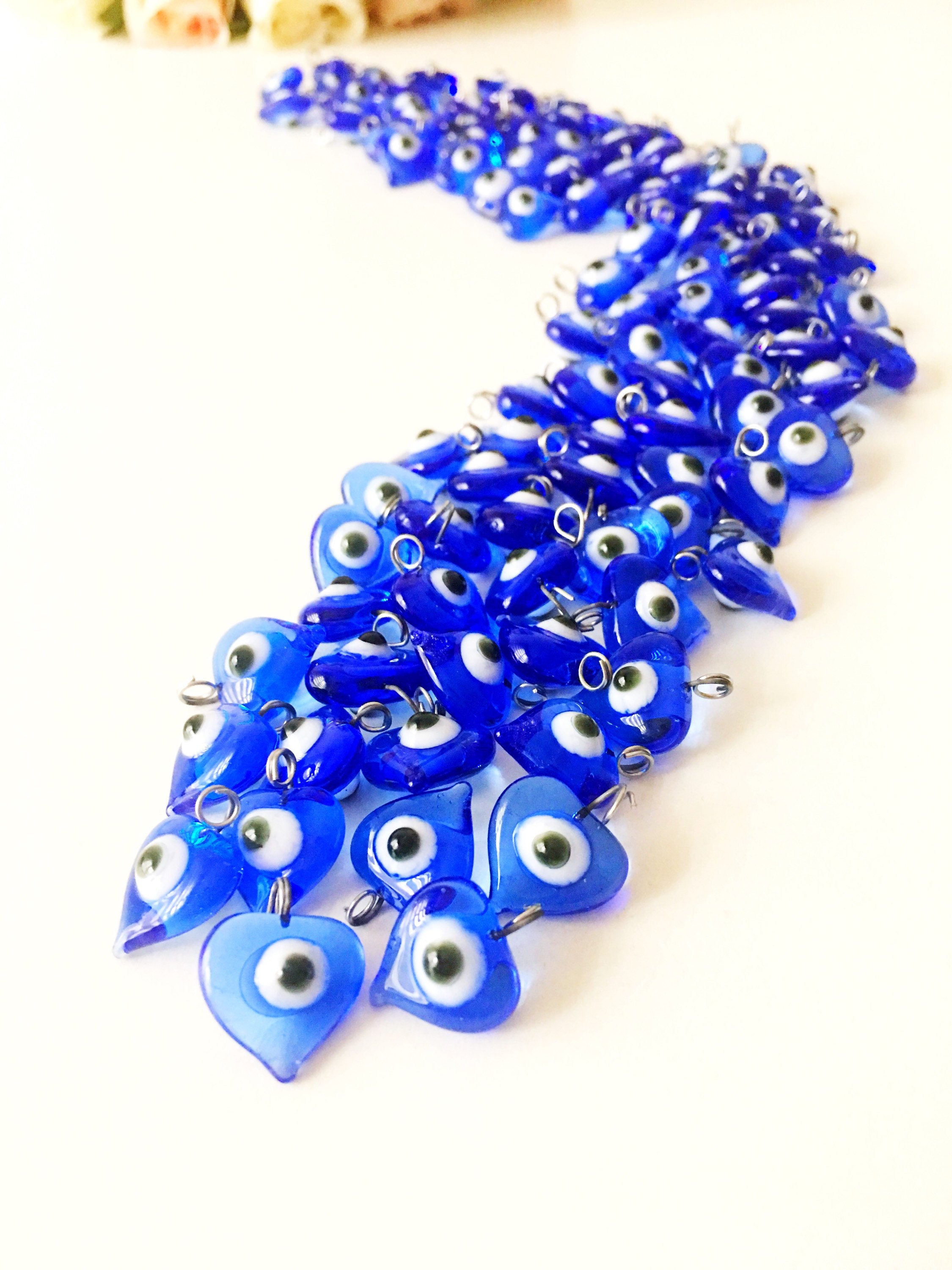 A collection of 100 unique blue evil eye charms with hooks, perfect for wedding favors and baby showers, displayed elegantly.