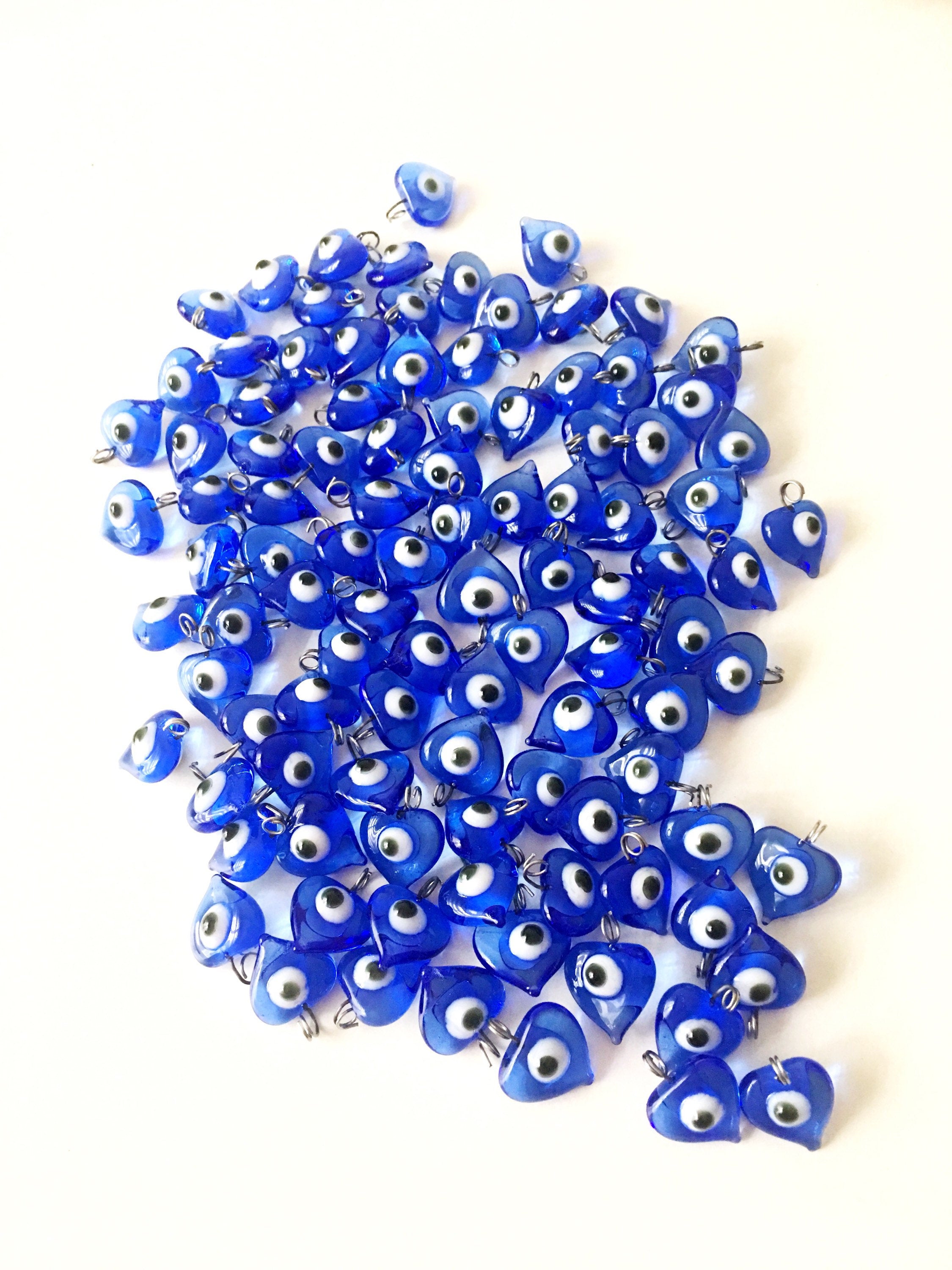 A collection of 100 unique blue evil eye charms with hooks, perfect for wedding favors and baby showers, displayed elegantly.