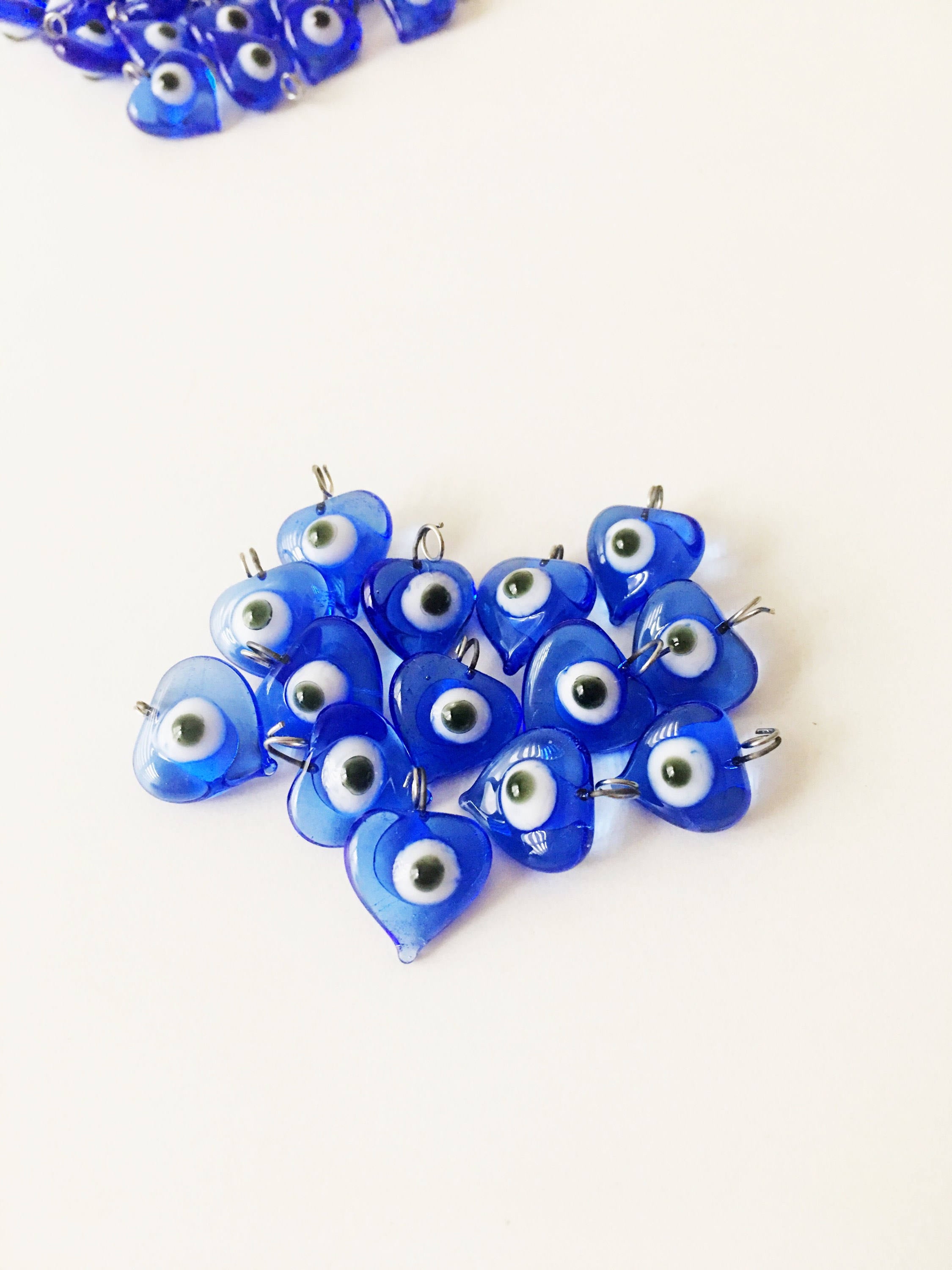 A collection of 100 unique blue evil eye charms with hooks, perfect for wedding favors and baby showers, displayed elegantly.