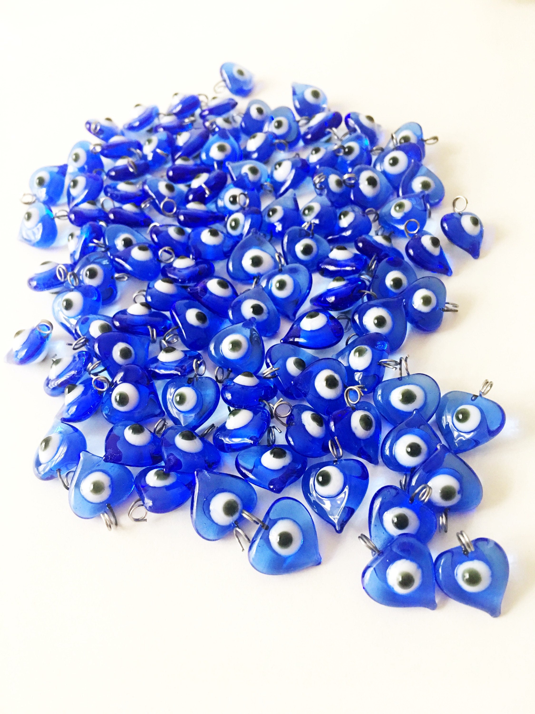 A collection of 100 unique blue evil eye charms with hooks, perfect for wedding favors and baby showers, displayed elegantly.