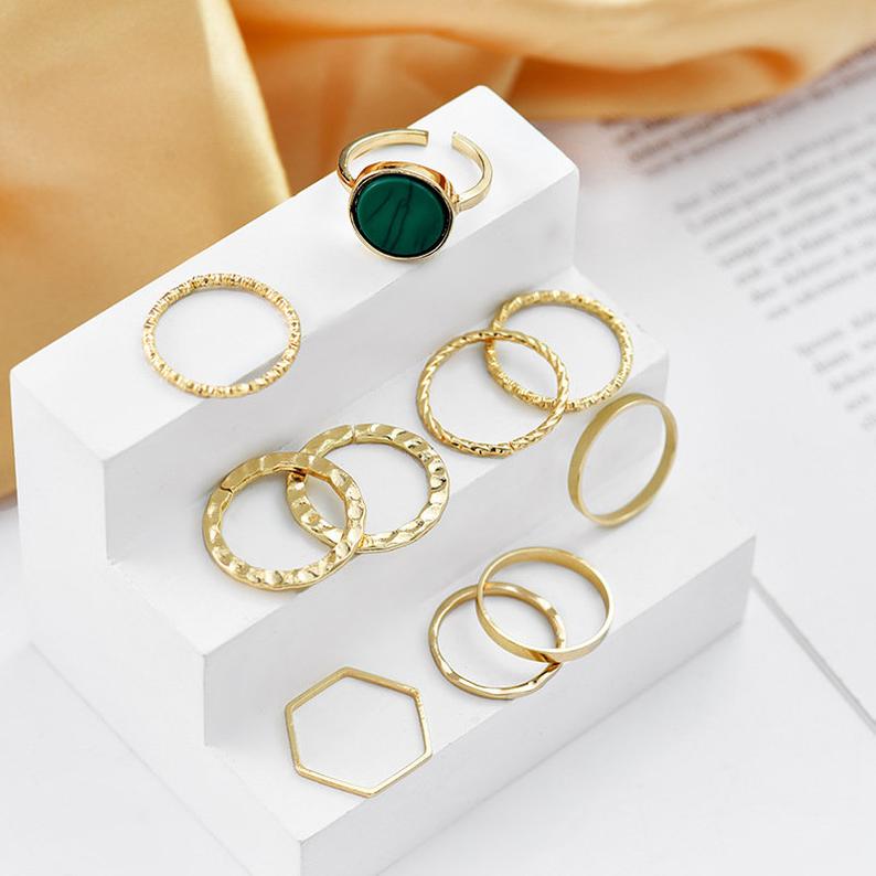 A stylish set of 10 silver stackable rings featuring a vibrant green stone, showcasing a bohemian and minimalistic design.