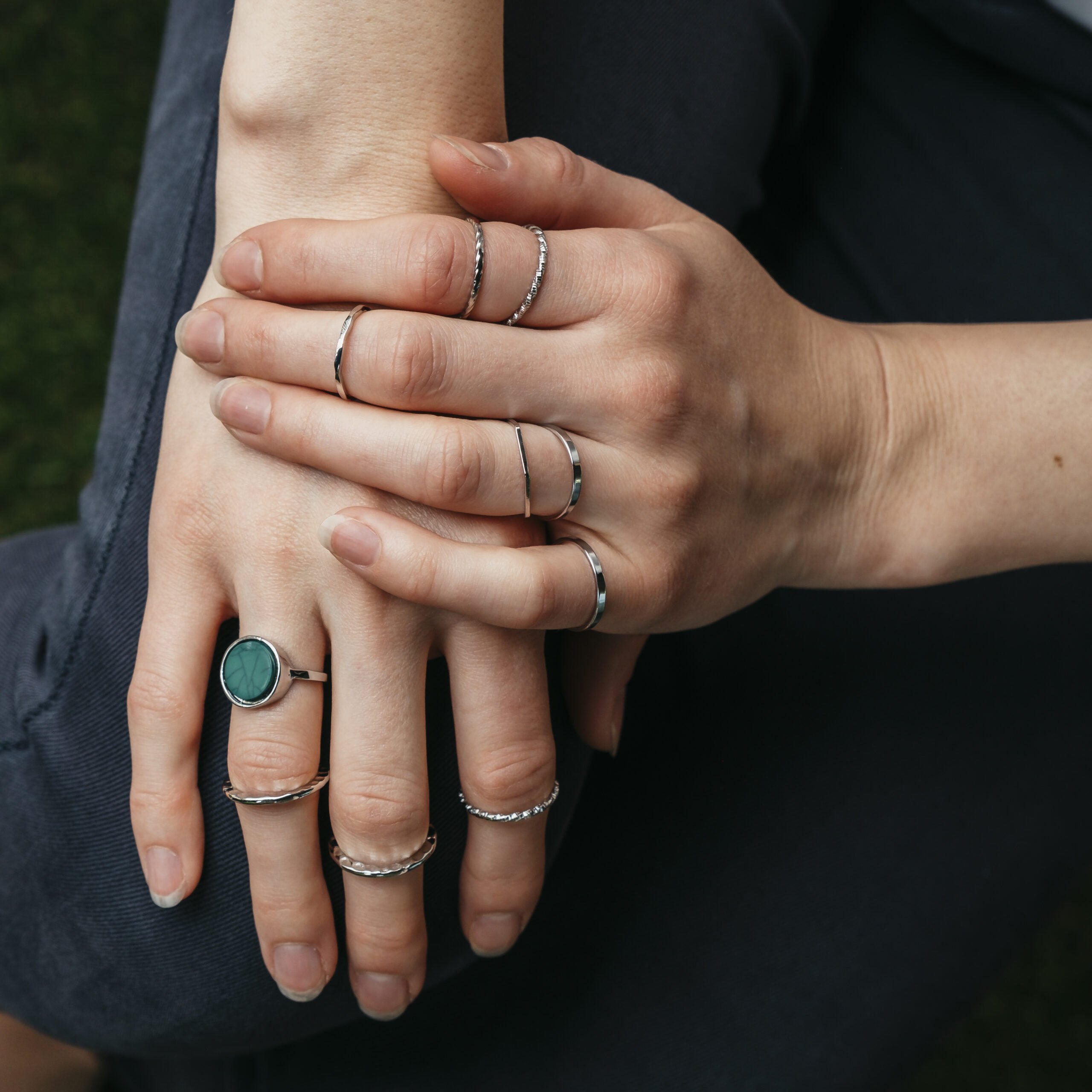 A stylish set of 10 silver stackable rings featuring a vibrant green stone, showcasing a bohemian and minimalistic design.