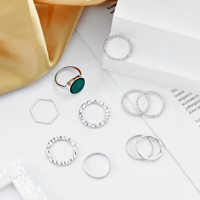 A stylish set of 10 silver stackable rings featuring a vibrant green stone, showcasing a bohemian and minimalistic design.