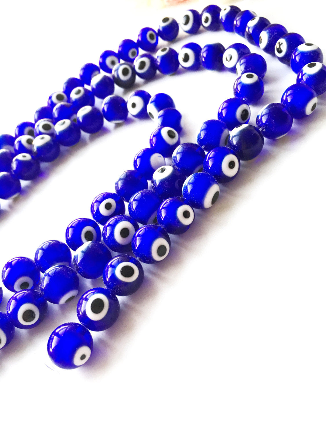 A strand of 12mm blue glass evil eye beads, showcasing their vibrant dark blue color and unique handmade designs.