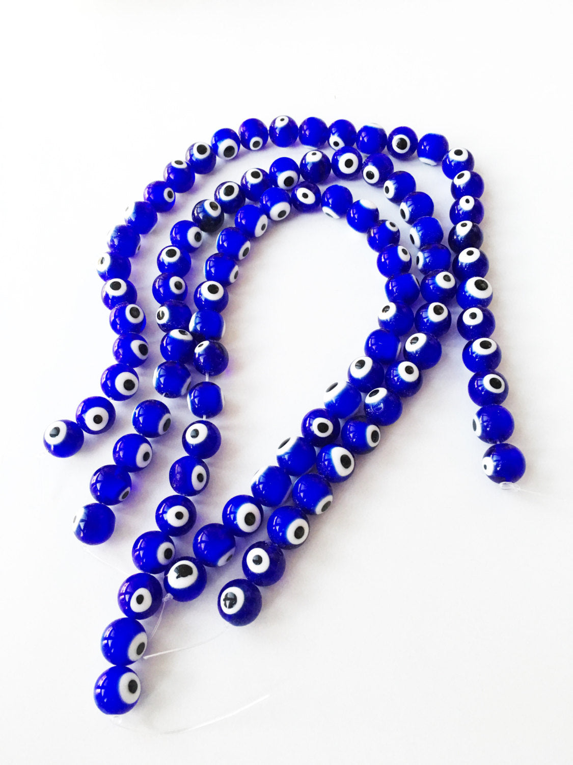 A strand of 12mm blue glass evil eye beads, showcasing their vibrant dark blue color and unique handmade designs.