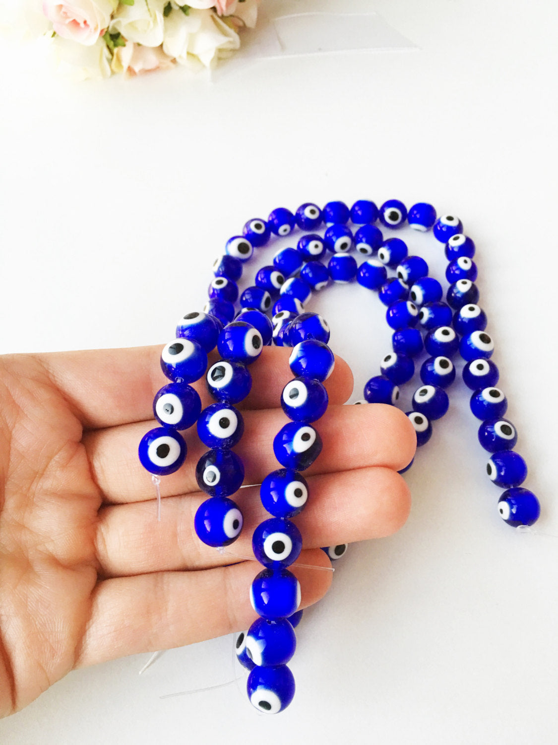 A strand of 12mm blue glass evil eye beads, showcasing their vibrant dark blue color and unique handmade designs.