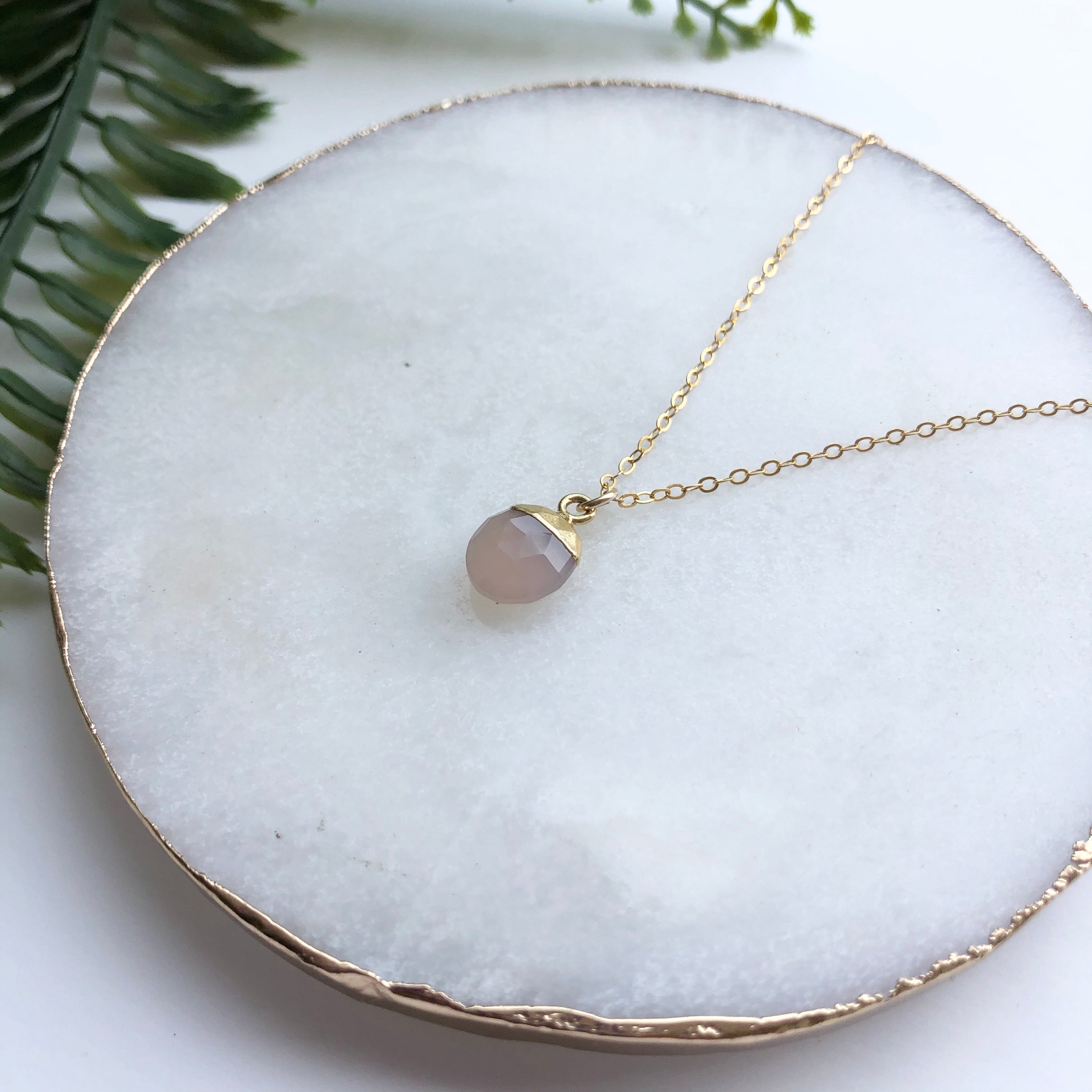 A delicate 14K gold filled necklace featuring a hand-cut Snow Pea pendant, elegantly displayed on a soft background.