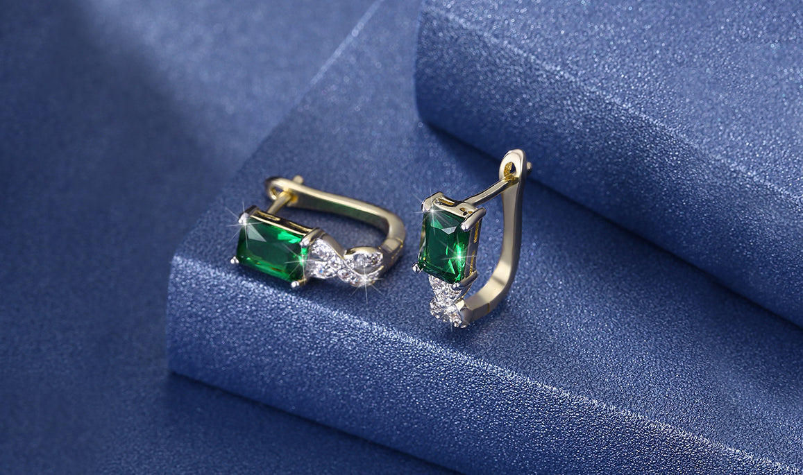 Elegant 14K gold plated earrings featuring emerald cut green stones in a twisted pavé design, perfect for any occasion.