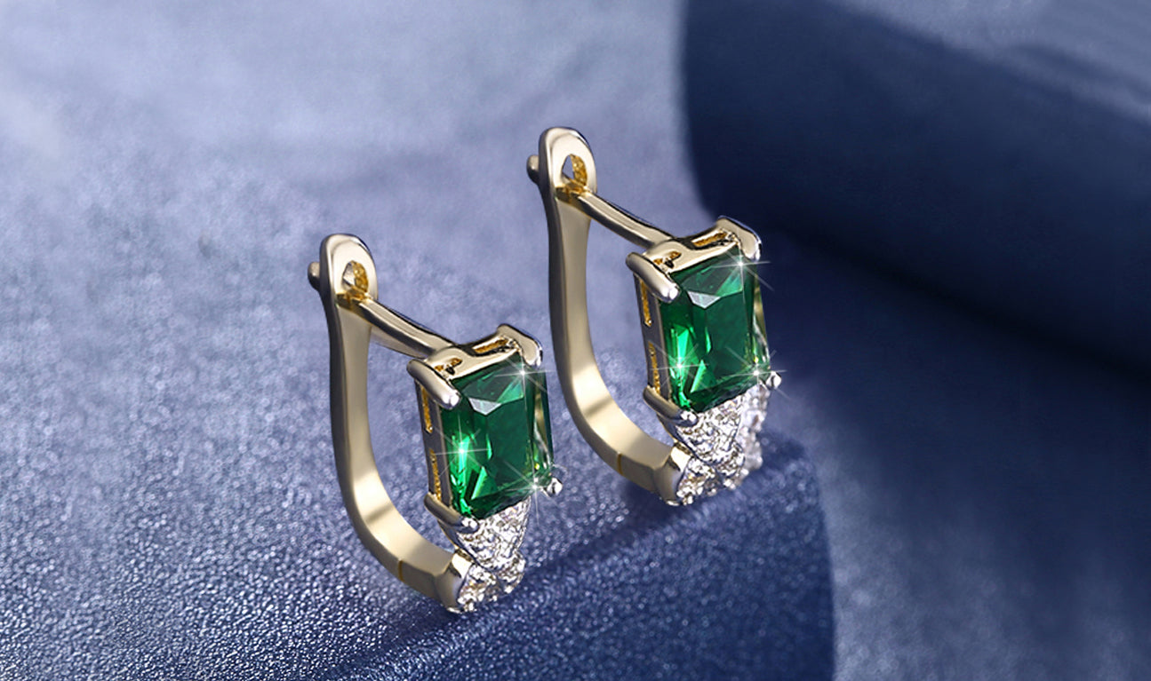 Elegant 14K gold plated earrings featuring emerald cut green stones in a twisted pavé design, perfect for any occasion.