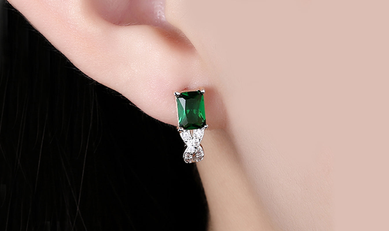 Elegant 14K gold plated earrings featuring emerald cut green stones in a twisted pavé design, perfect for any occasion.