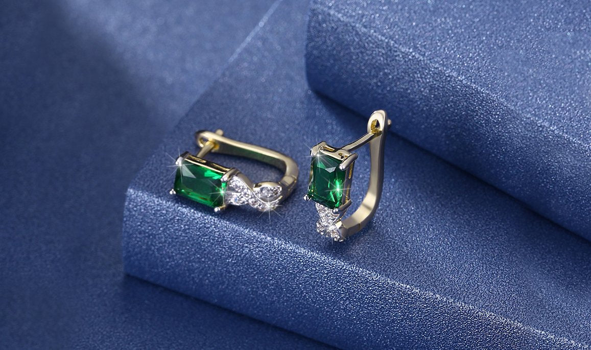 Elegant 14K gold plated lever back earrings featuring emerald cut green stones in a twisted pav'e design.