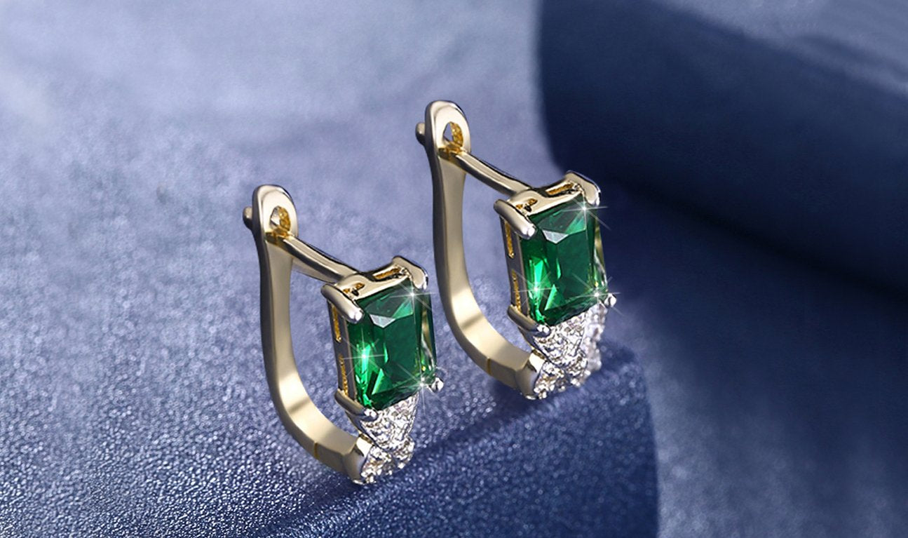 Elegant 14K gold plated lever back earrings featuring emerald cut green stones in a twisted pav'e design.