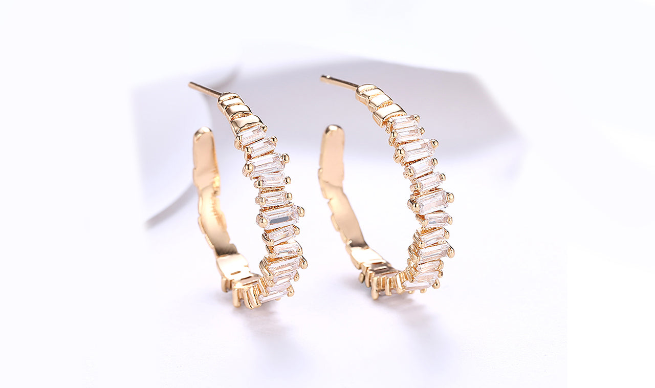 Elegant 14K gold plated earrings featuring emerald cut white sapphires, showcasing a unique asymmetrical design.