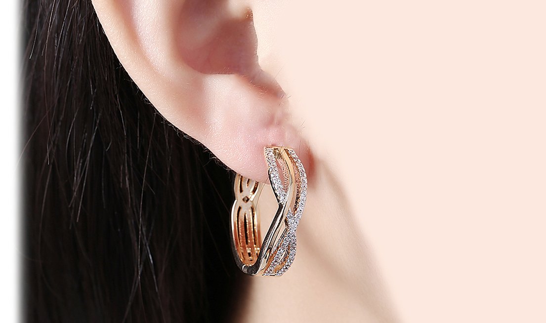 Elegant 14K gold plated clip-on earrings featuring white Austrian elements in a twisted abstract design.