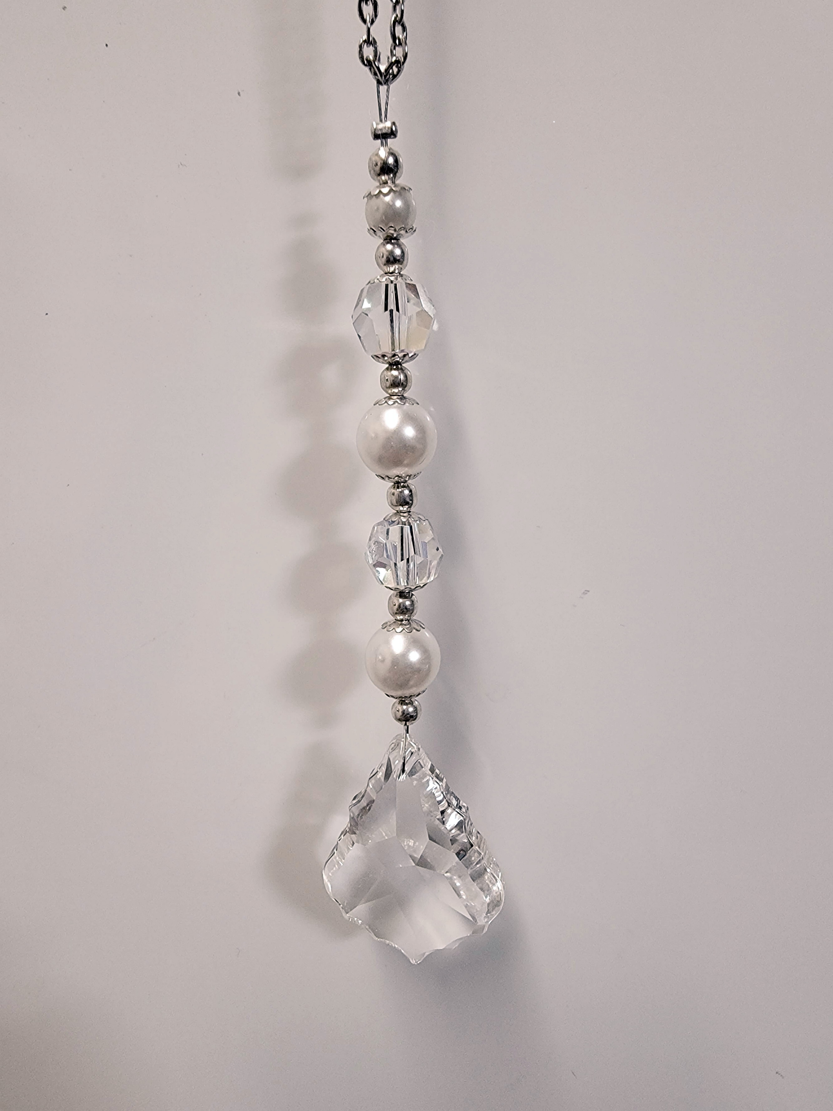 A 1.5 inch Crystal French Cut Suncatcher featuring a prism, round crystal beads, white glass pearls, and silver-toned beads, sparkling in sunlight.