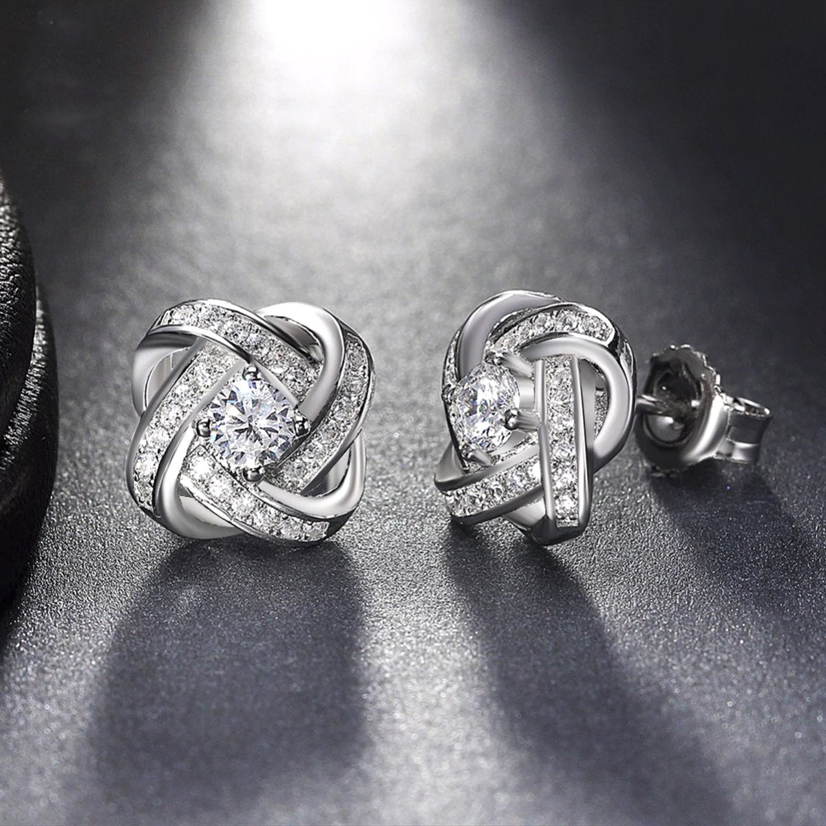 Elegant 18K white gold plated infinity twist stud earrings featuring sparkling Austrian crystals.