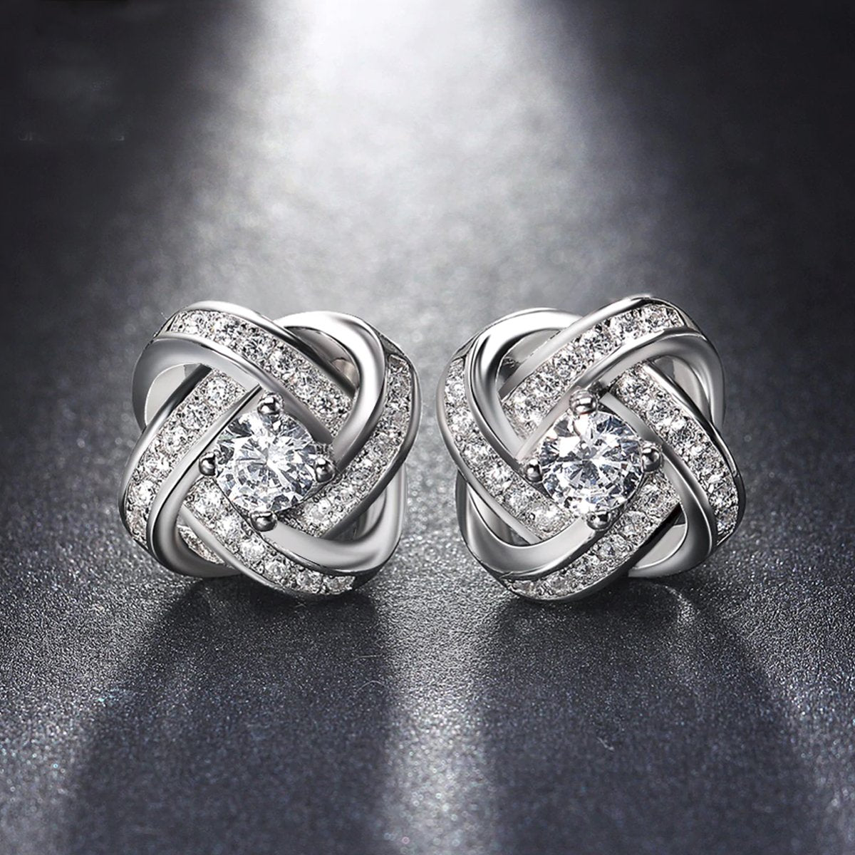 Elegant 18K white gold plated infinity twist stud earrings featuring sparkling Austrian crystals.