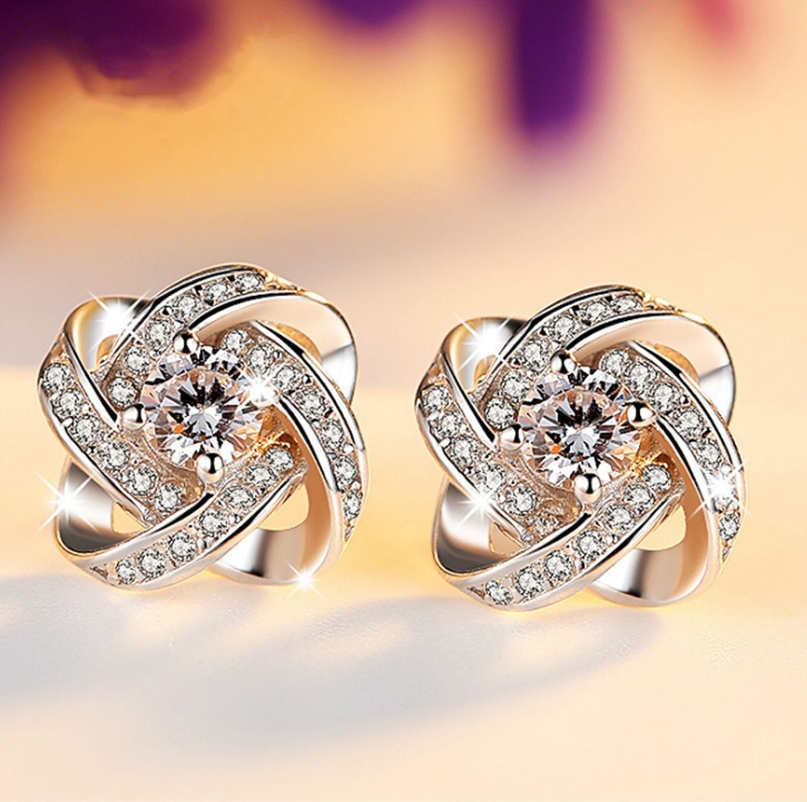 Elegant 18K white gold plated infinity twist stud earrings featuring sparkling Austrian crystals.