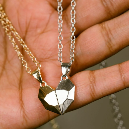 Two heart-shaped magnetic pendants on a minimalist chain, available in gold and silver, symbolizing love and connection.