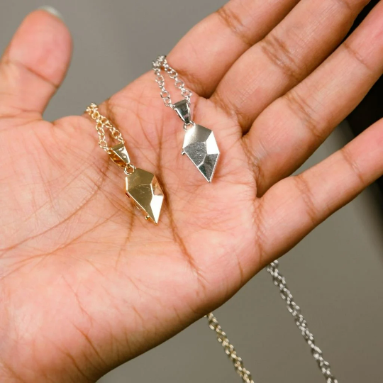 Two heart-shaped magnetic pendants on a minimalist chain, available in gold and silver, symbolizing love and connection.