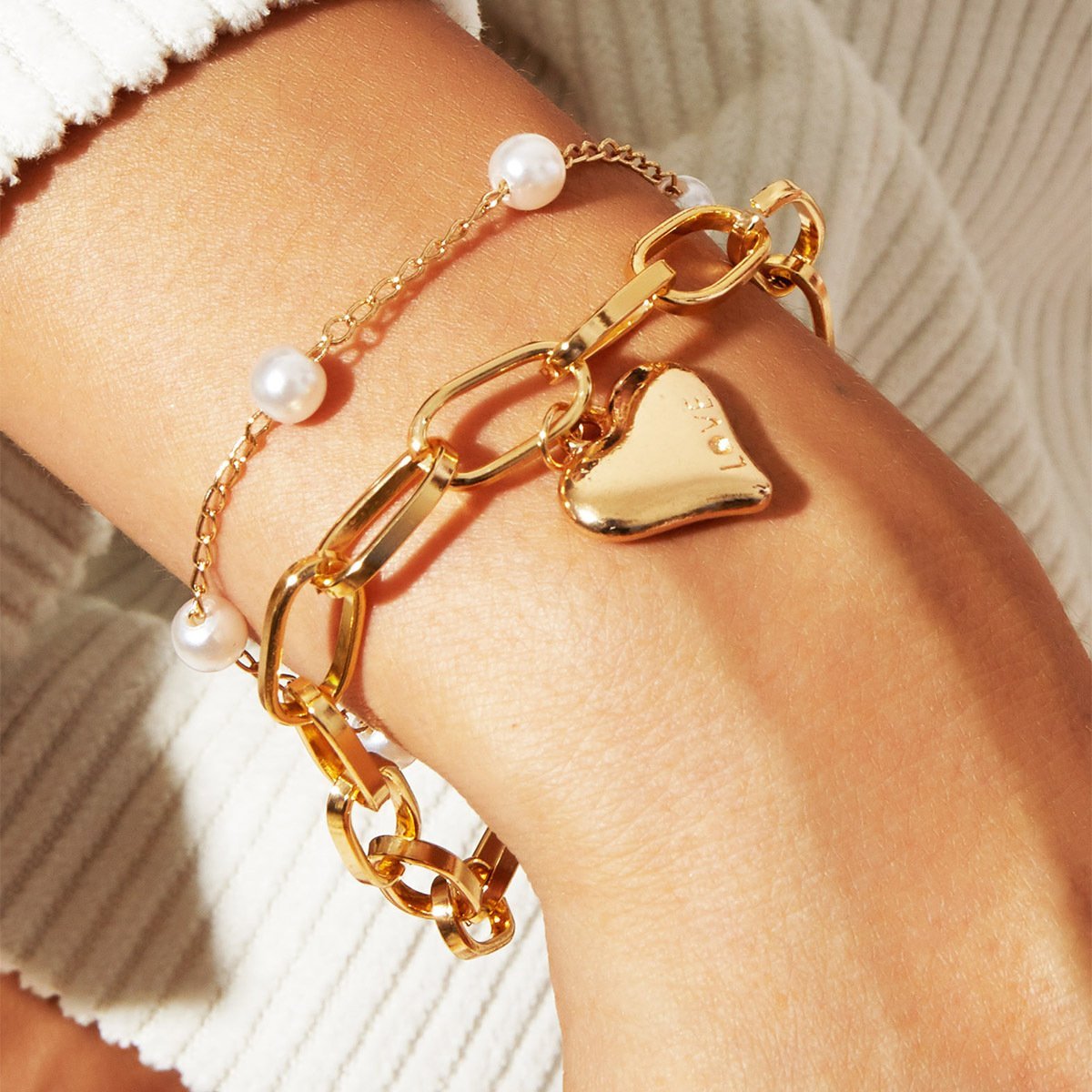 A beautiful 2 Piece Heart and Pearl Bracelet Set, elegantly designed with 18K gold plating, showcasing a heart motif and pearl accents.