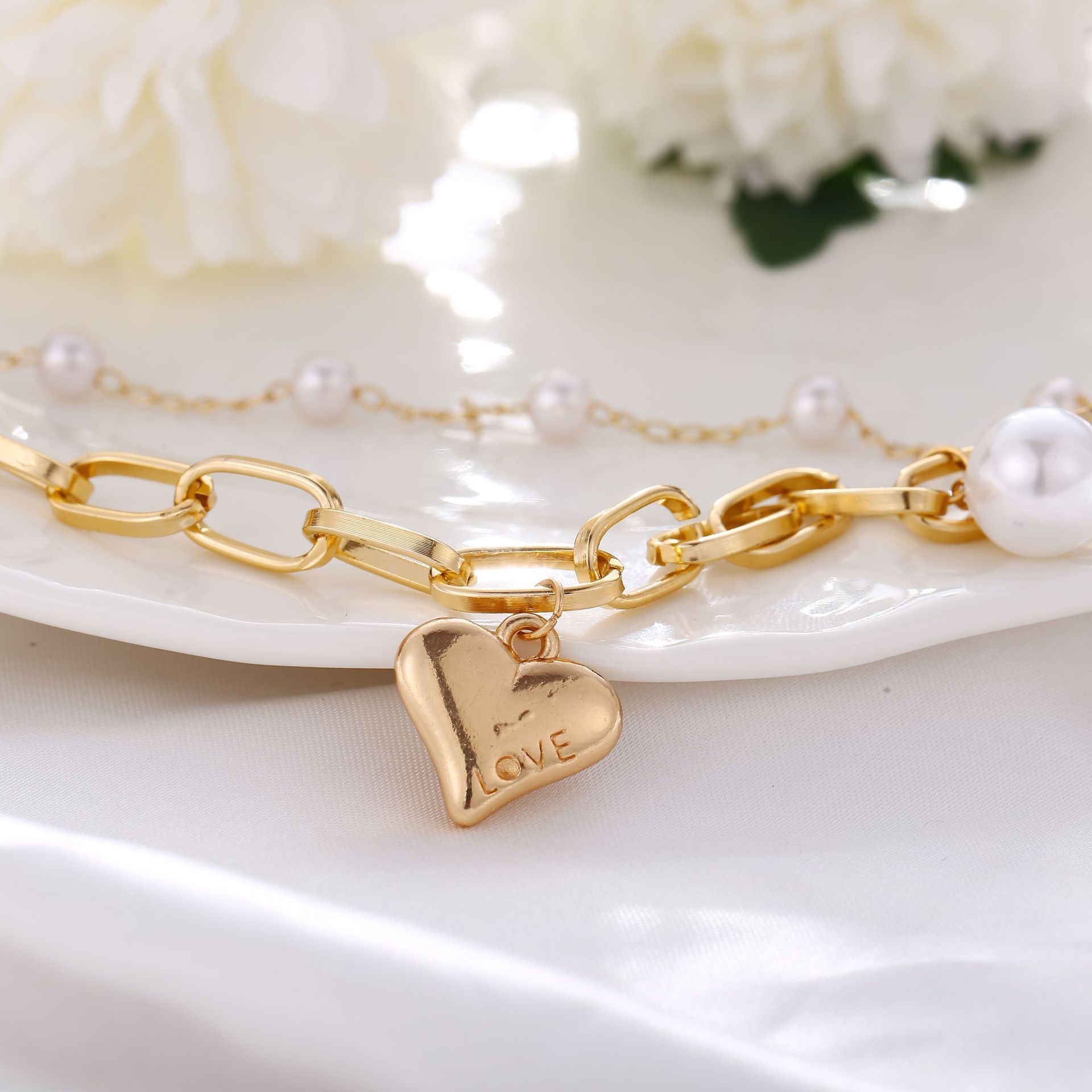 A beautiful 2 Piece Heart and Pearl Bracelet Set, elegantly designed with 18K gold plating, showcasing a heart motif and pearl accents.