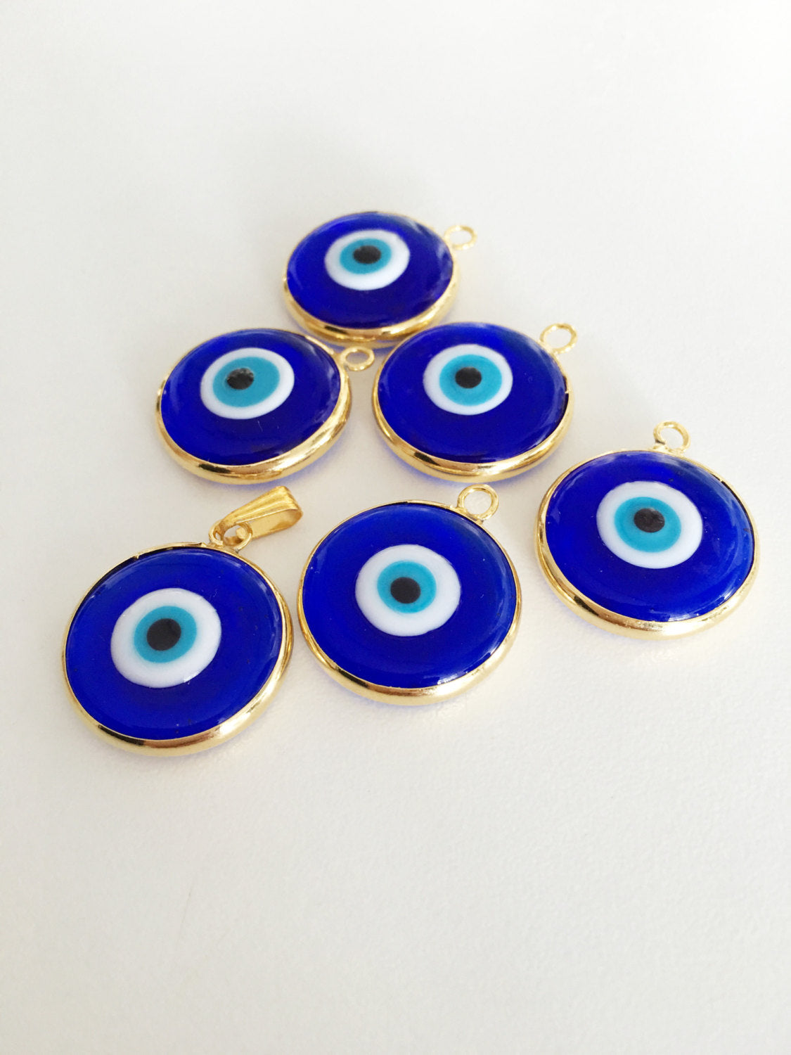 Two gold plated evil eye pendants, 22mm diameter, featuring dark blue and opaque blue glass charms, showcasing intricate Turkish craftsmanship.