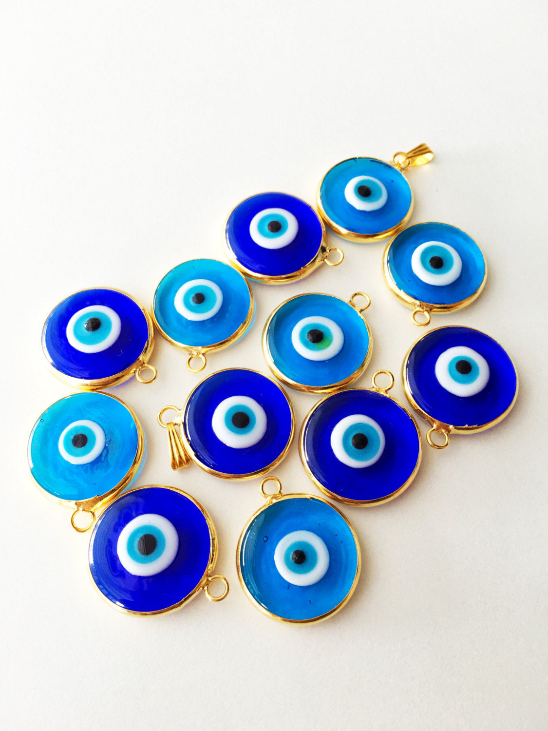 Two gold plated evil eye pendants, 22mm diameter, featuring dark blue and opaque blue glass charms, showcasing intricate Turkish craftsmanship.