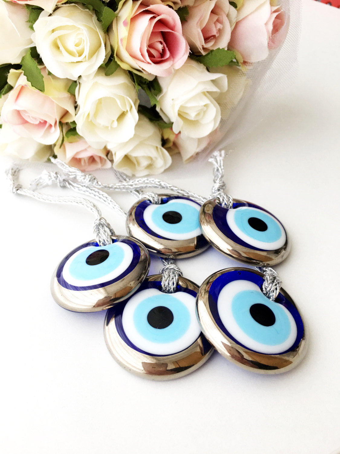 Two handmade silver evil eye beads, each 4.5cm, with a gold rope for hanging, showcasing intricate designs.