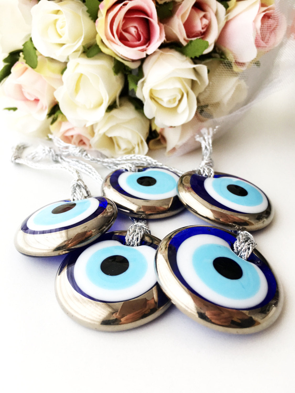 Two handmade silver evil eye beads, each 4.5cm, with a gold rope for hanging, showcasing intricate designs.