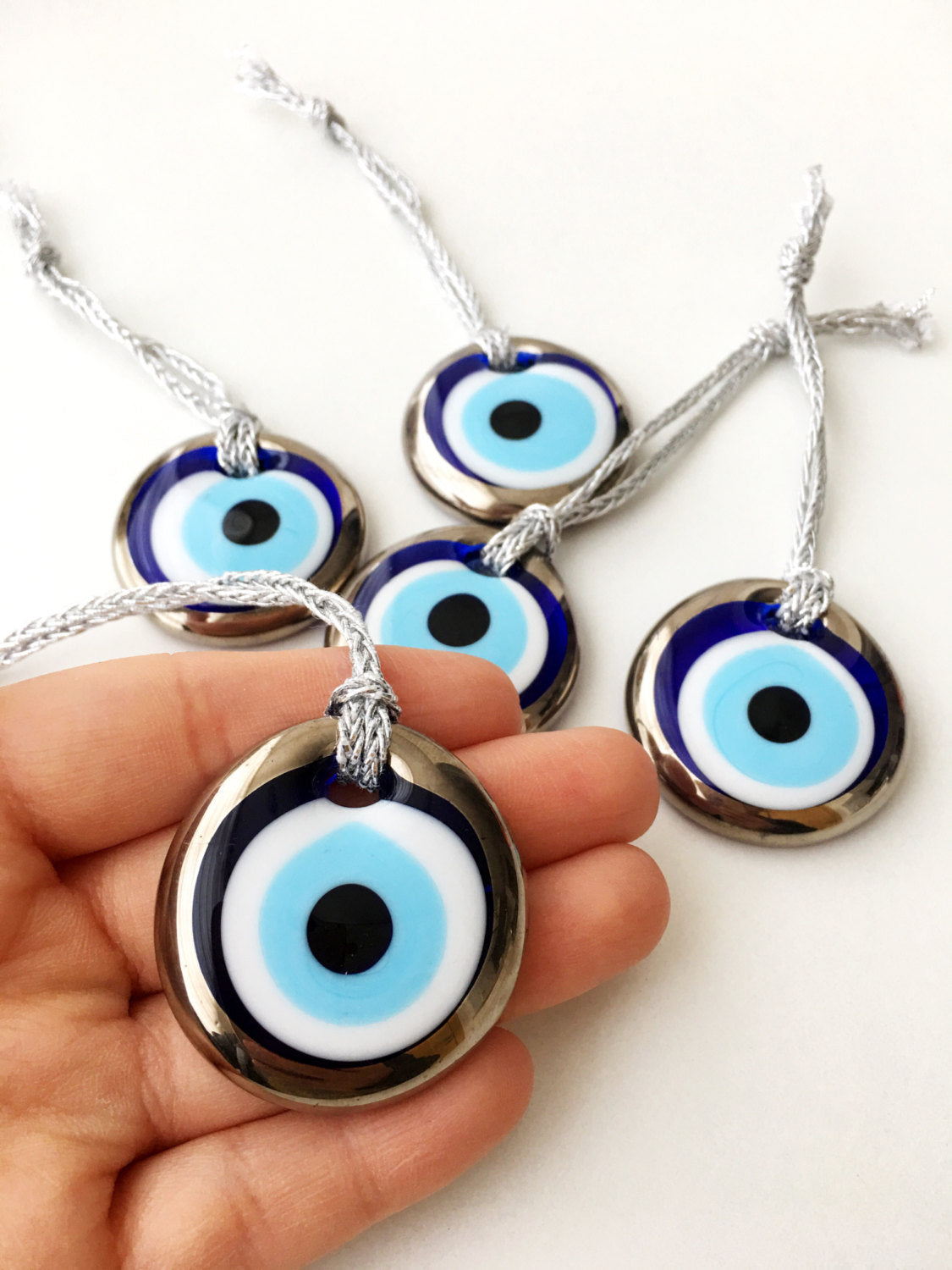 Two handmade silver evil eye beads, each 4.5cm, with a gold rope for hanging, showcasing intricate designs.