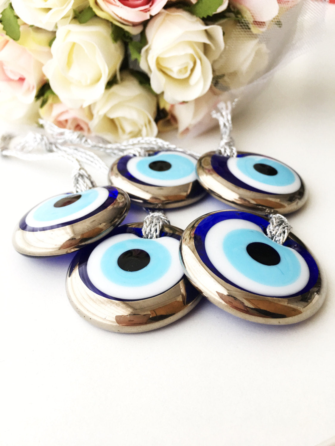 Two handmade silver evil eye beads, each 4.5cm, with a gold rope for hanging, showcasing intricate designs.