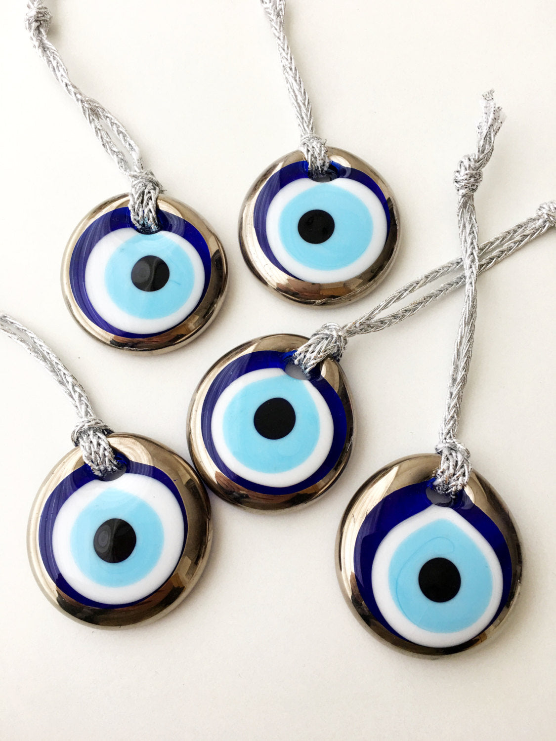 Two handmade silver evil eye beads, each 4.5cm, with a gold rope for hanging, showcasing intricate designs.