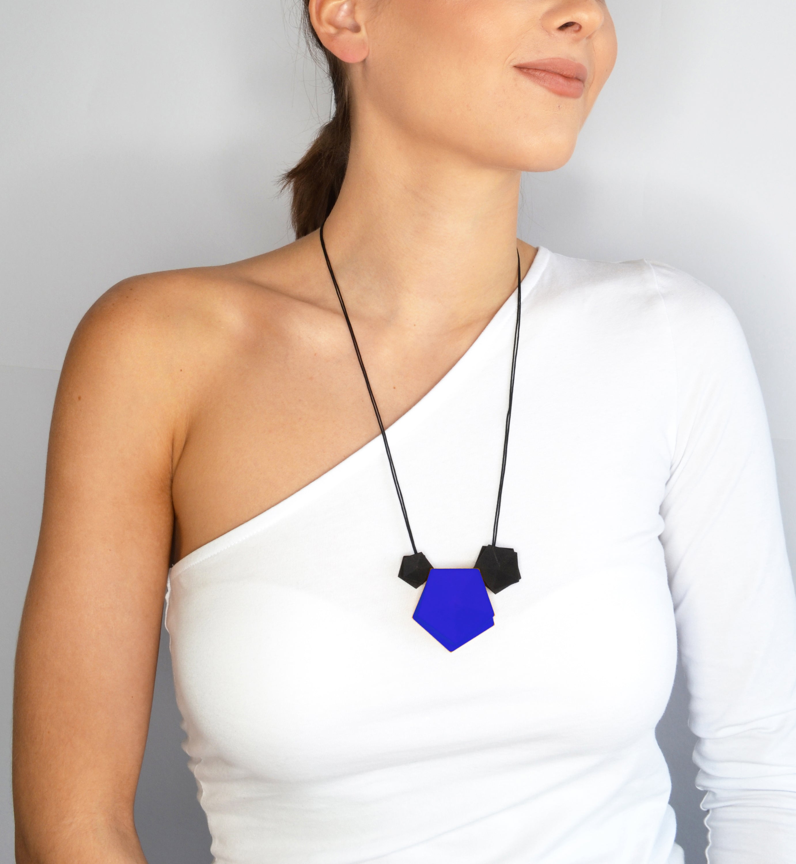 Vertigo 3 Element Necklace featuring three geometric pentagons on a black nylon cord, showcasing vibrant colors and a sterling silver bead for length adjustment.