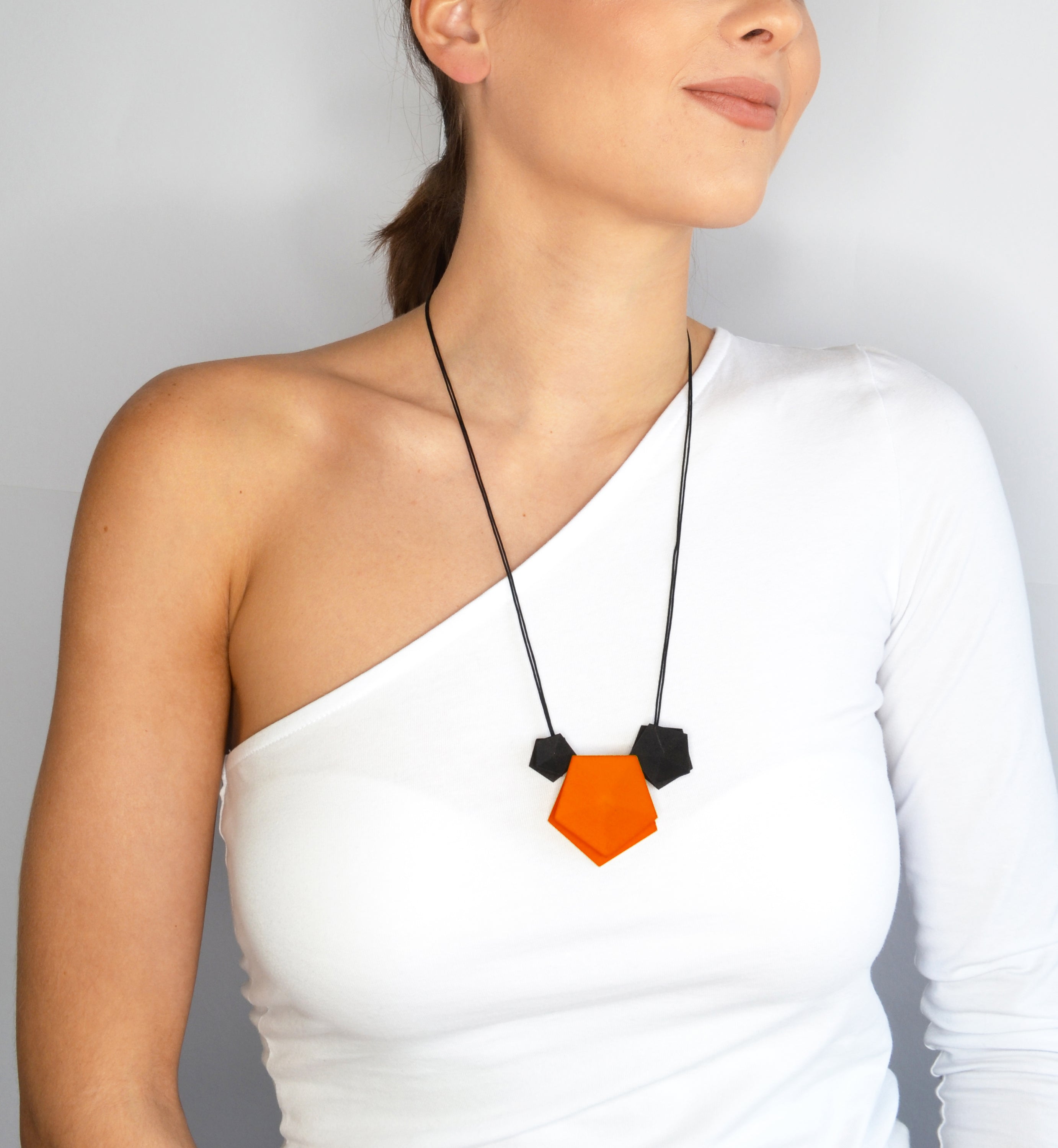 Vertigo 3 Element Necklace featuring three geometric pentagons on a black nylon cord, showcasing vibrant colors and a sterling silver bead for length adjustment.