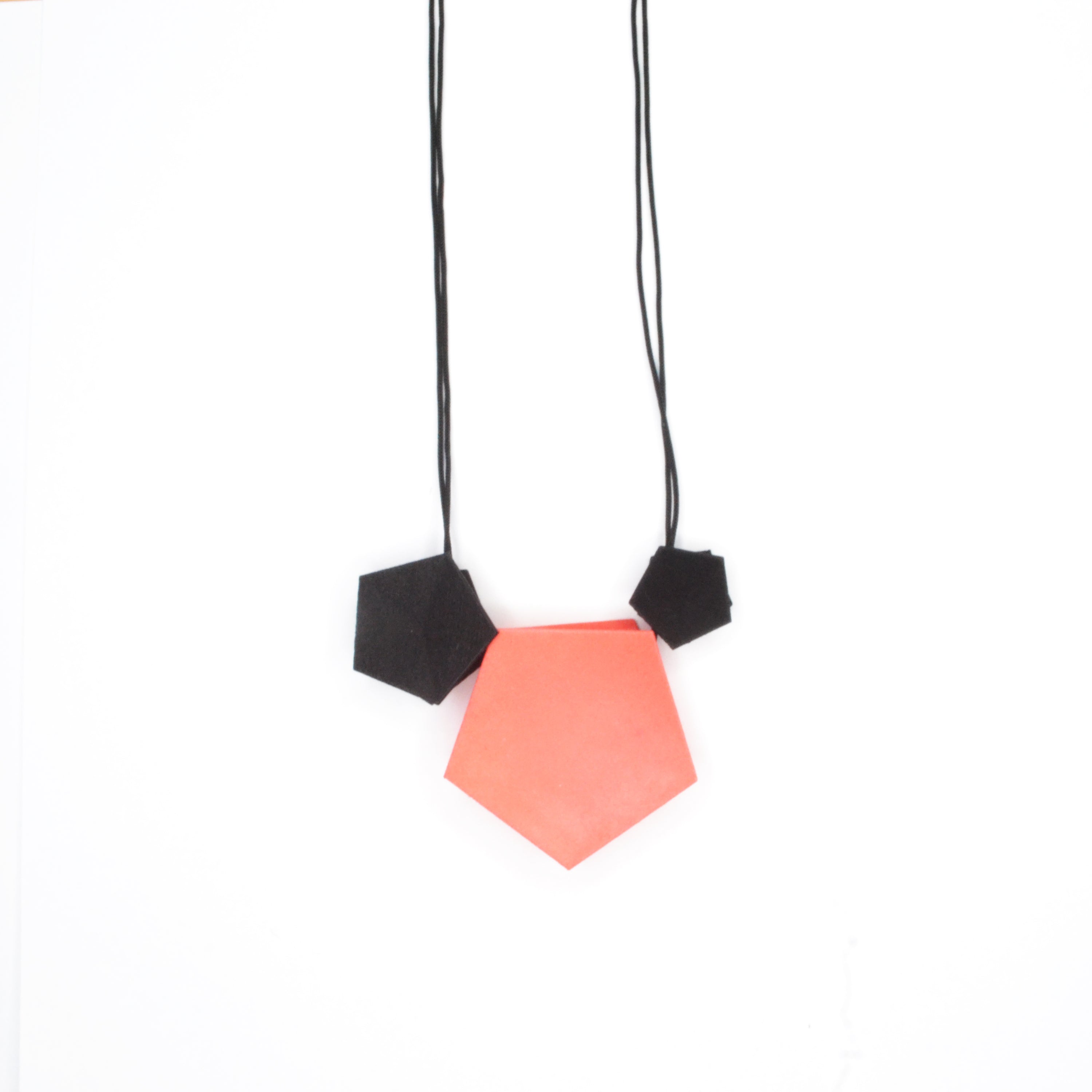 Vertigo 3 Element Necklace featuring three geometric pentagons on a black nylon cord, showcasing vibrant colors and a sterling silver bead for length adjustment.